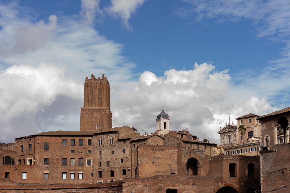 Stunning view of ancient Roman buildings in Rome with bright blue sky and clouds.