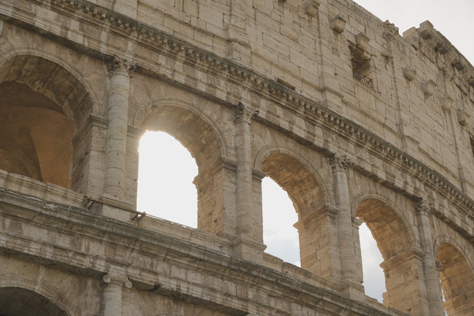 Close-up of the iconic Roman Colosseum arches with sunlight streaming through. Architectural marvel.