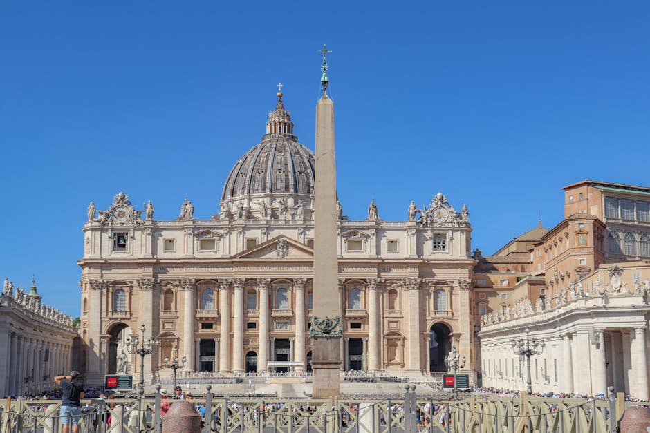 St. Peter's Basilica and the Vatican Obelisk under a clear blue sky. Iconic religious site in Vatican City.