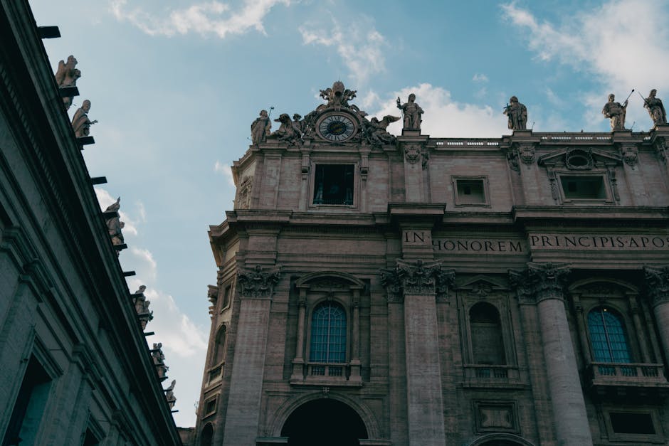 St. Peter's Basilica facade with statues under a clear blue sky, capturing timeless beauty.